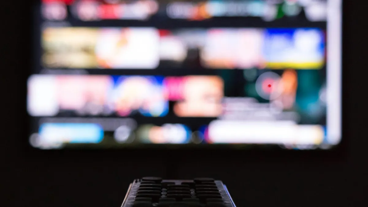 TV remote pointed at a screen full of apps, choosing the best IPTV player app