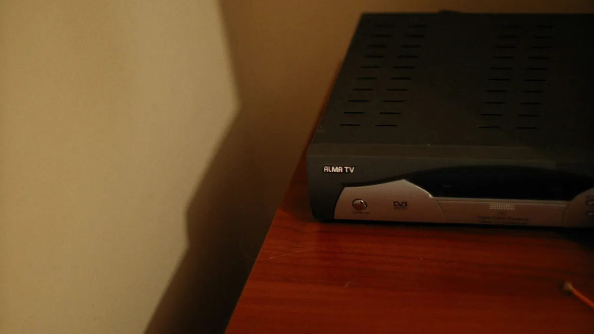 Black set-top box on a wooden cabinet, the kind of device used for an IPTV MAG box setup