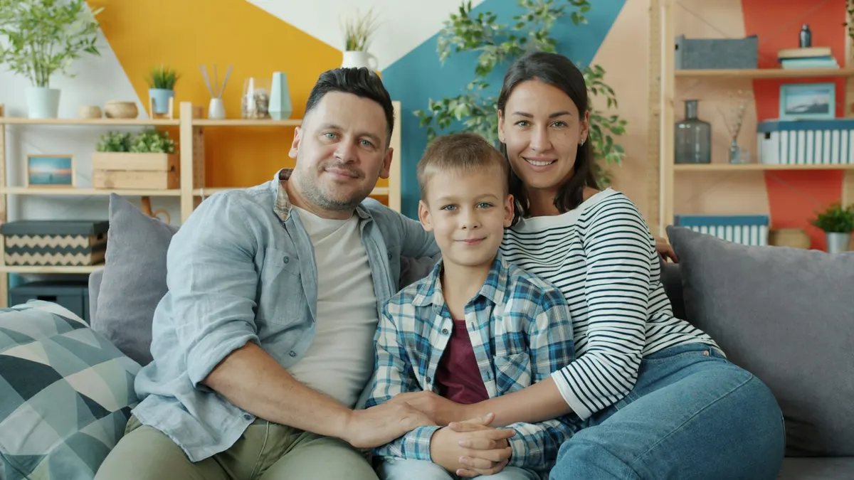 Family of three on a sofa at home, deciding between IPTV vs Netflix in New Zealand