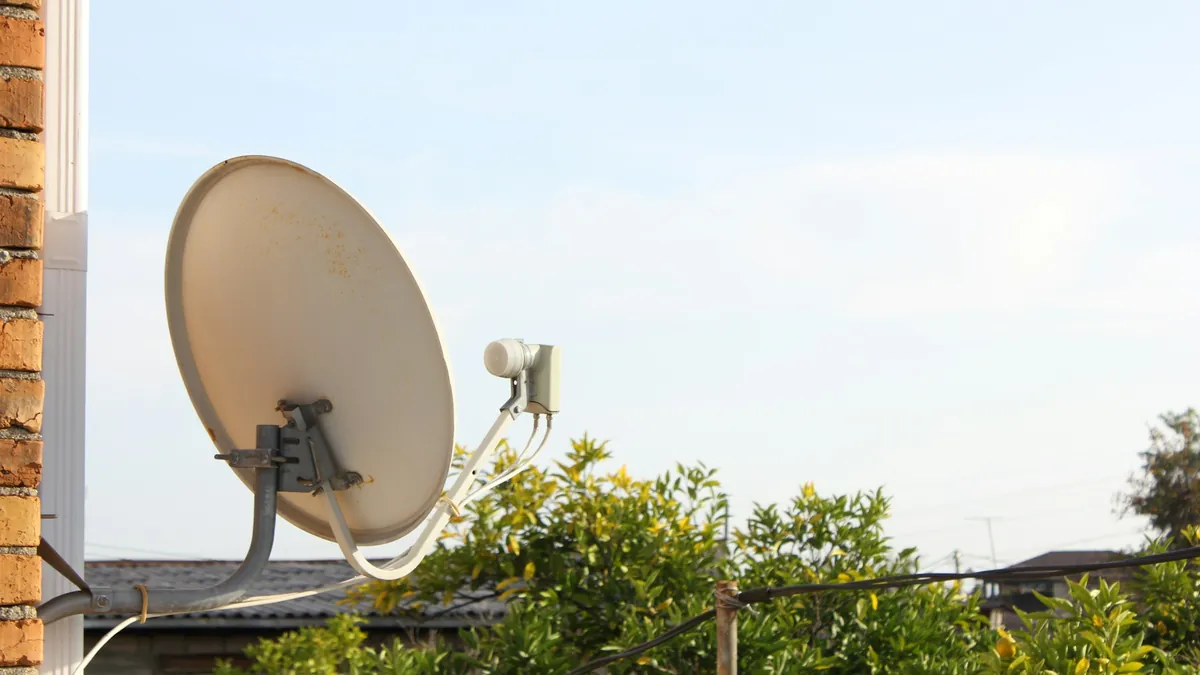 Satellite dish on a house wall, the traditional way to get pay TV compared with IPTV in New Zealand