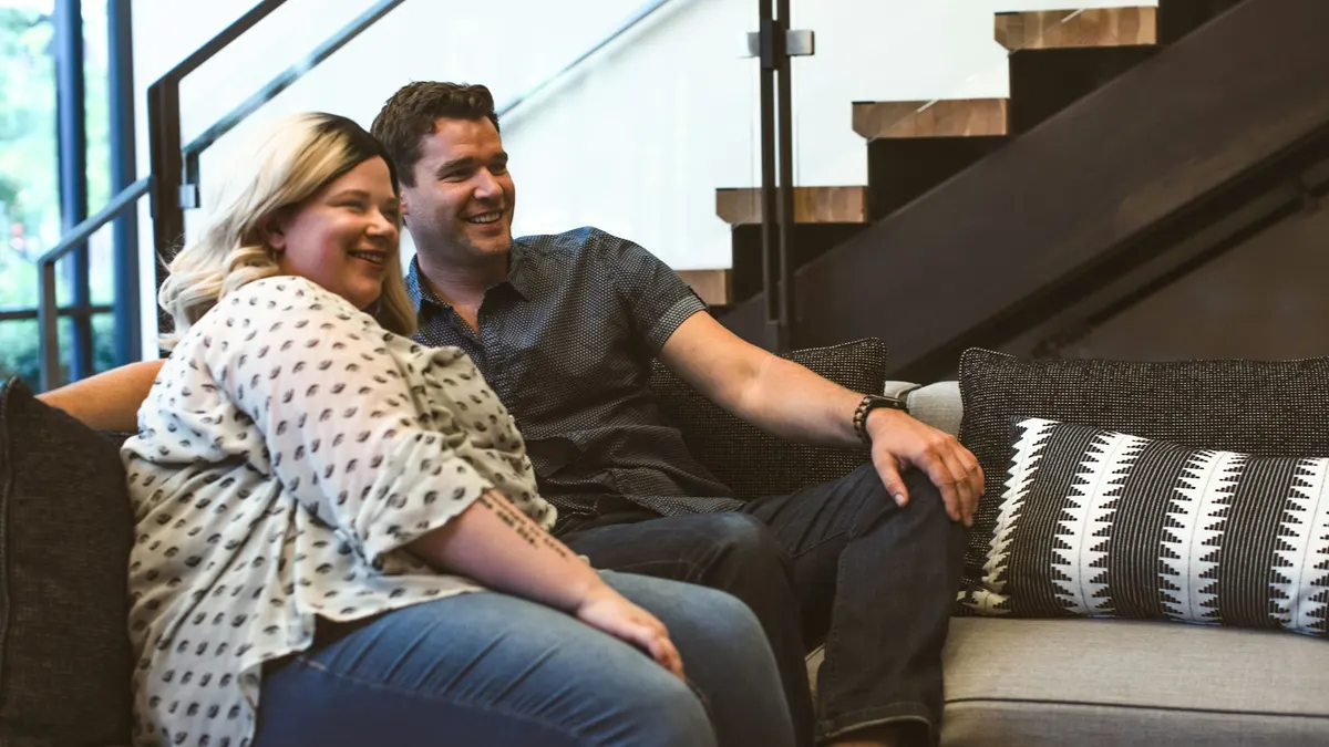 Couple relaxing on a sofa at home, watching live sport with a Sky Sport Now pass in New Zealand