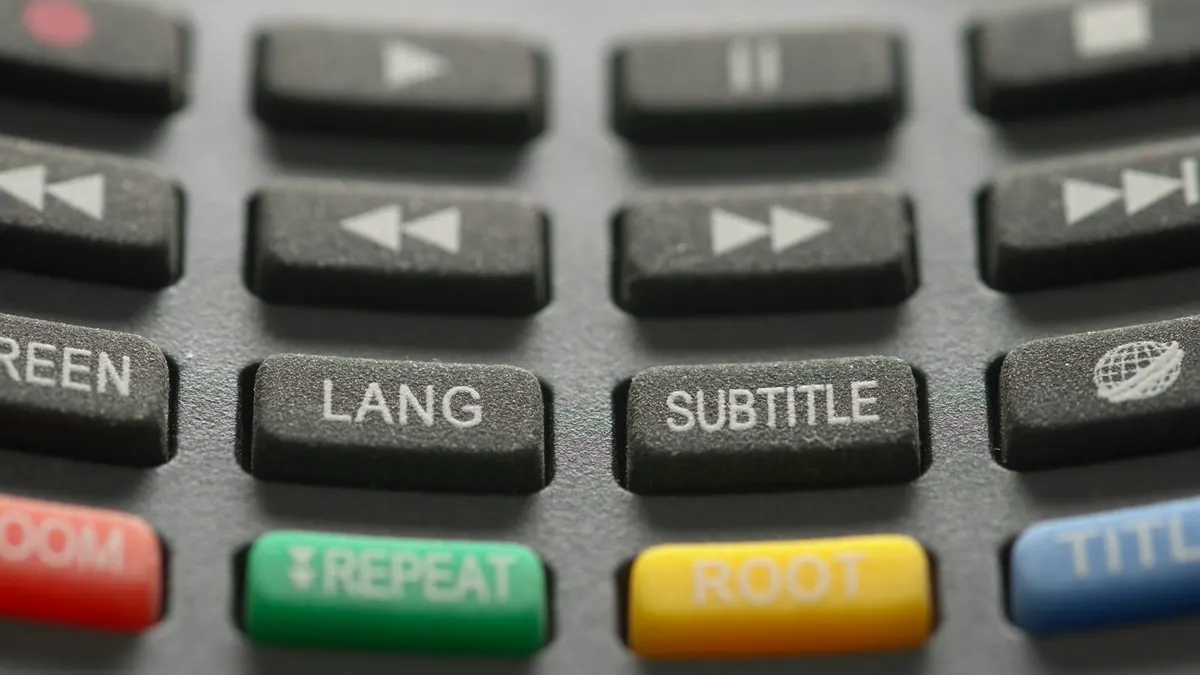 Close-up of TV remote buttons for playback, subtitles and repeat, used during TiviMate setup